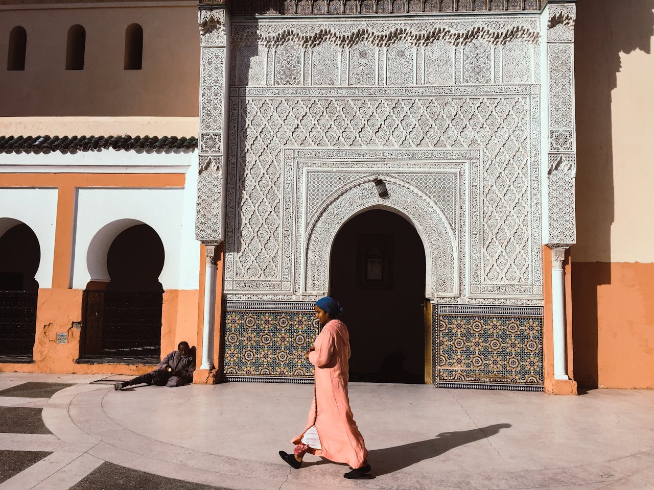 A person walks past an intricately designed Moroccan building in Marrakesh.