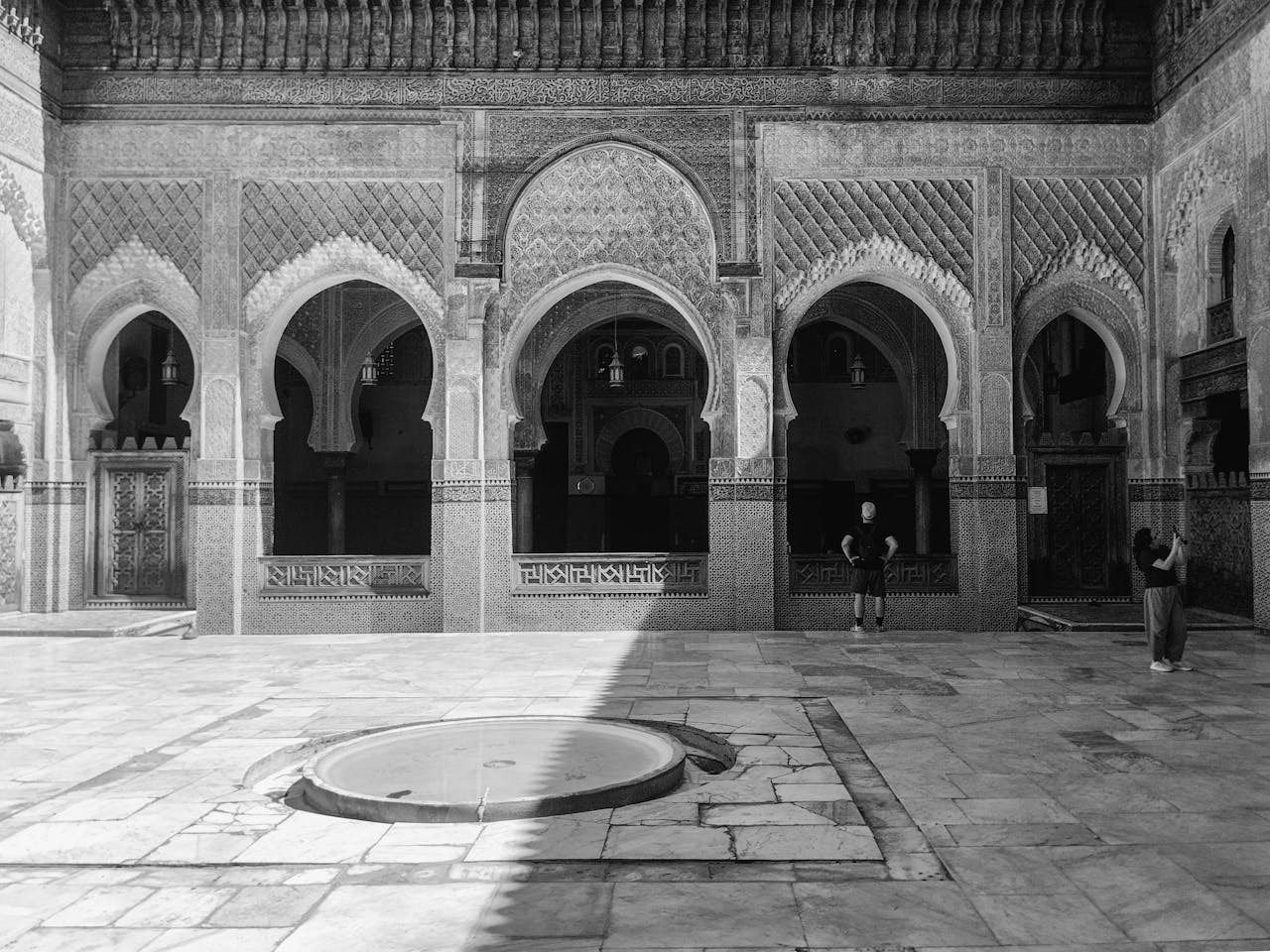 Black and white image showcasing traditional Moroccan arches and tilework in Fes Medina.